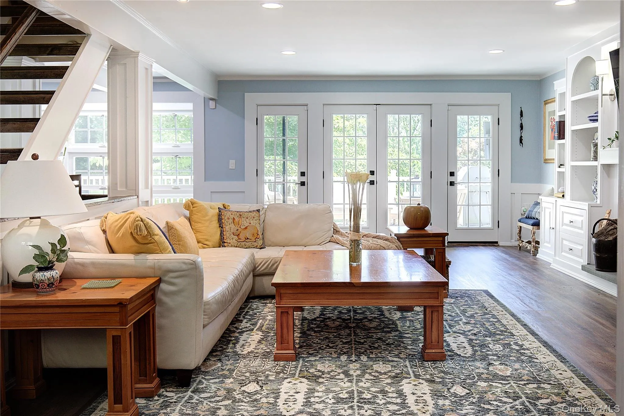 Living room with wainscoting, wood finished floors, ornamental molding, recessed lighting, and a decorative wall Living room with wainscoting, wood finished floors, ornamental molding, recessed lighting, and a decorative wall