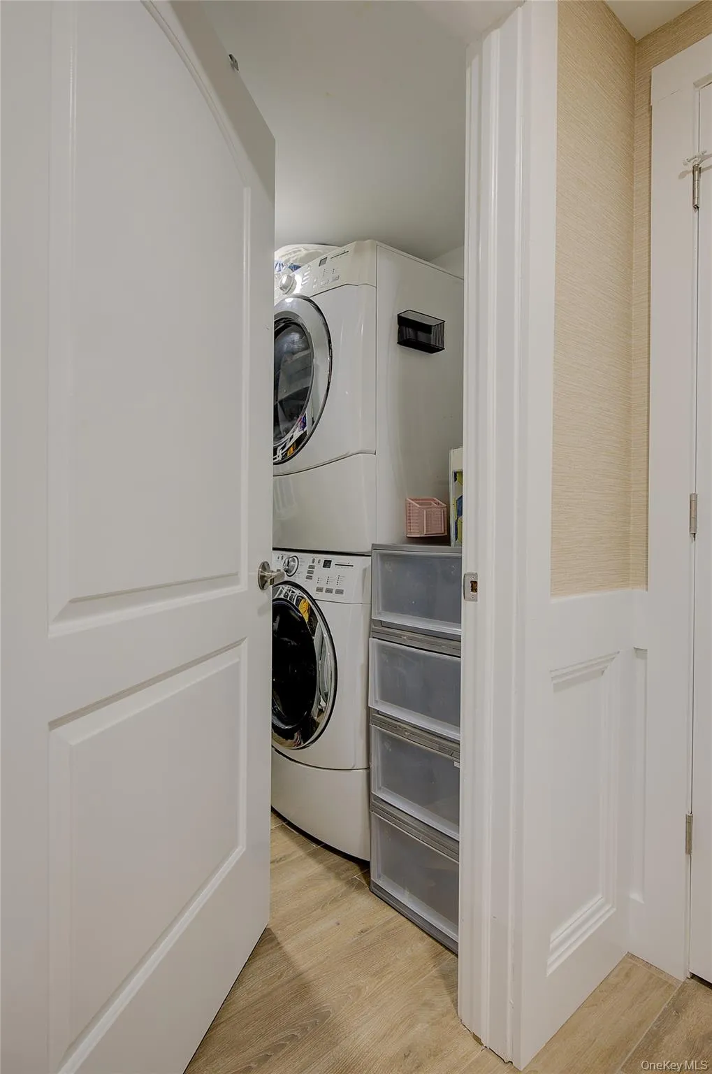 Laundry area with light wood-style floors and stacked washer / dryer Laundry area with light wood-style floors and stacked washer / dryer