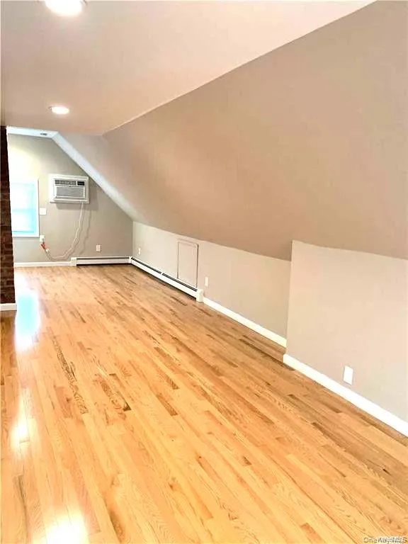 Bonus room with light wood-style floors, lofted ceiling, a wall mounted AC, and recessed lighting Bonus room with light wood-style floors, lofted ceiling, a wall mounted AC, and recessed lighting