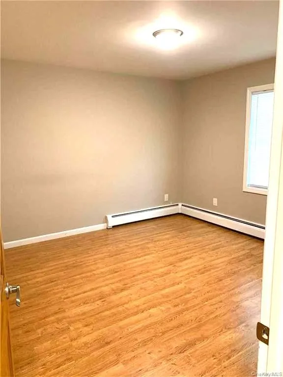 Spare room featuring light wood-style floors and a baseboard radiator Spare room featuring light wood-style floors and a baseboard radiator