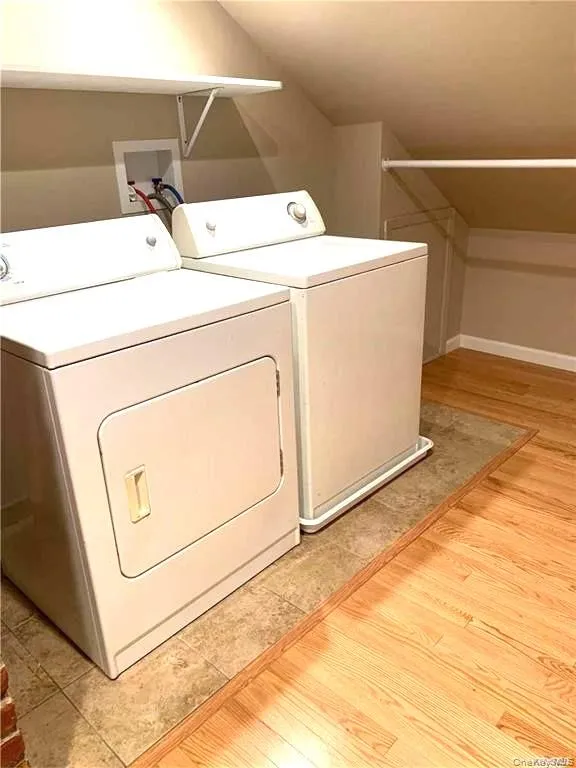 Washroom with light wood finished floors, washer and dryer, and vaulted ceiling Washroom with light wood finished floors, washer and dryer, and vaulted ceiling