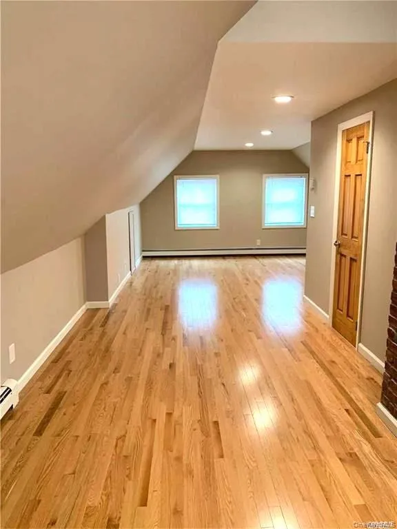 Additional living space featuring light wood-style flooring, vaulted ceiling, recessed lighting, and baseboard heating Additional living space featuring light wood-style flooring, vaulted ceiling, recessed lighting, and baseboard heating