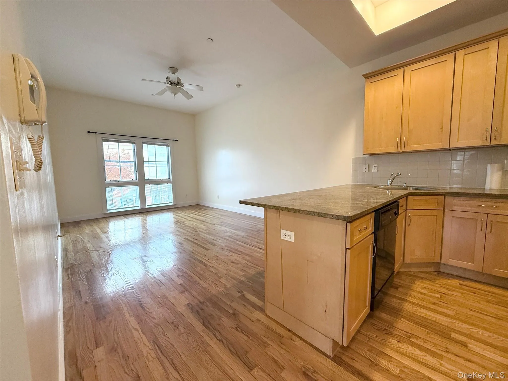 Kitchen featuring decorative backsplash, light wood finished floors, open floor plan, a peninsula, and a ceiling fan Kitchen featuring decorative backsplash, light wood finished floors, open floor plan, a peninsula, and a ceiling fan