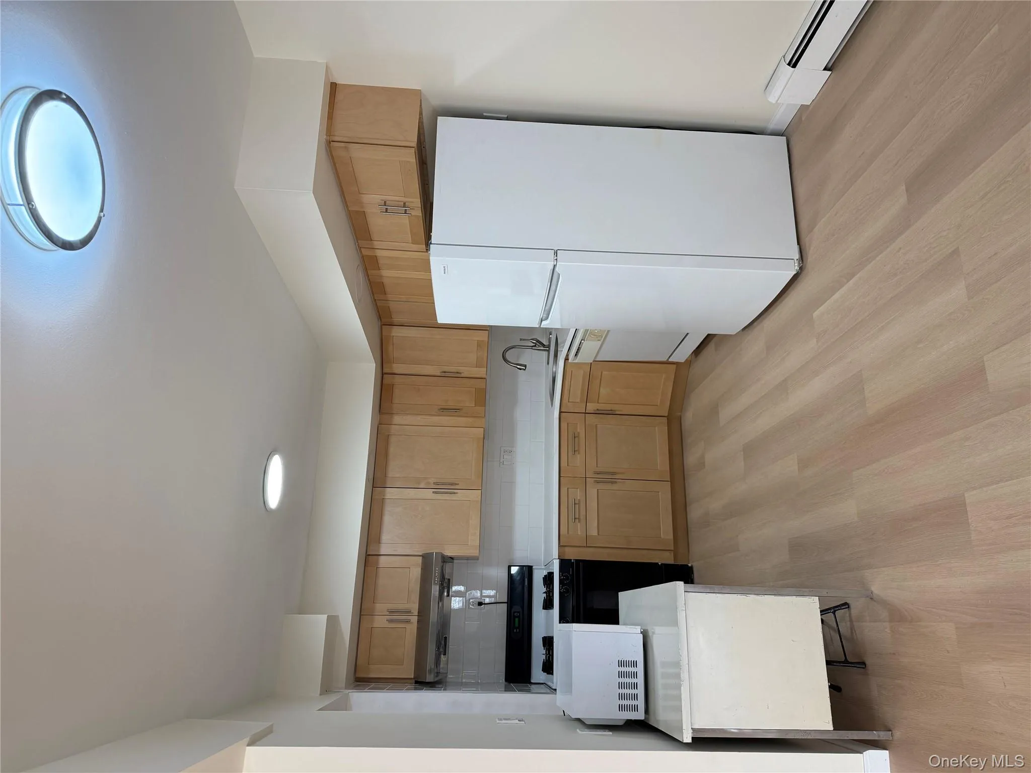 Kitchen featuring light countertops, refrigerator, range, a baseboard radiator, and light wood finished floors Kitchen featuring light countertops, refrigerator, range, a baseboard radiator, and light wood finished floors