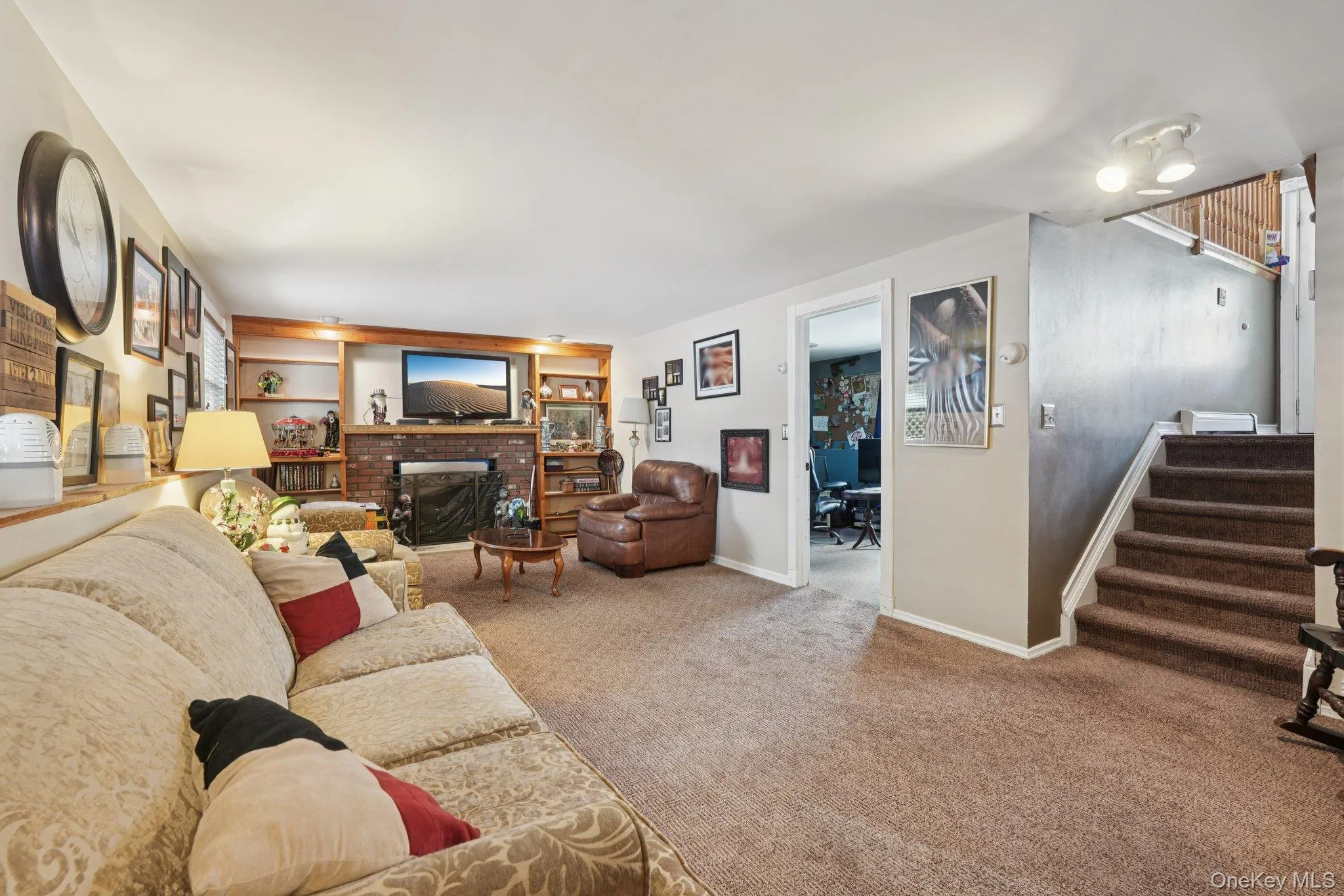 Lower level Living room with carpet floors, a brick fireplace, and stairway.some photos may include virtually staged or digitally modified Lower level Living room with carpet floors, a brick fireplace, and stairway.some photos may include virtually staged or digitally modified