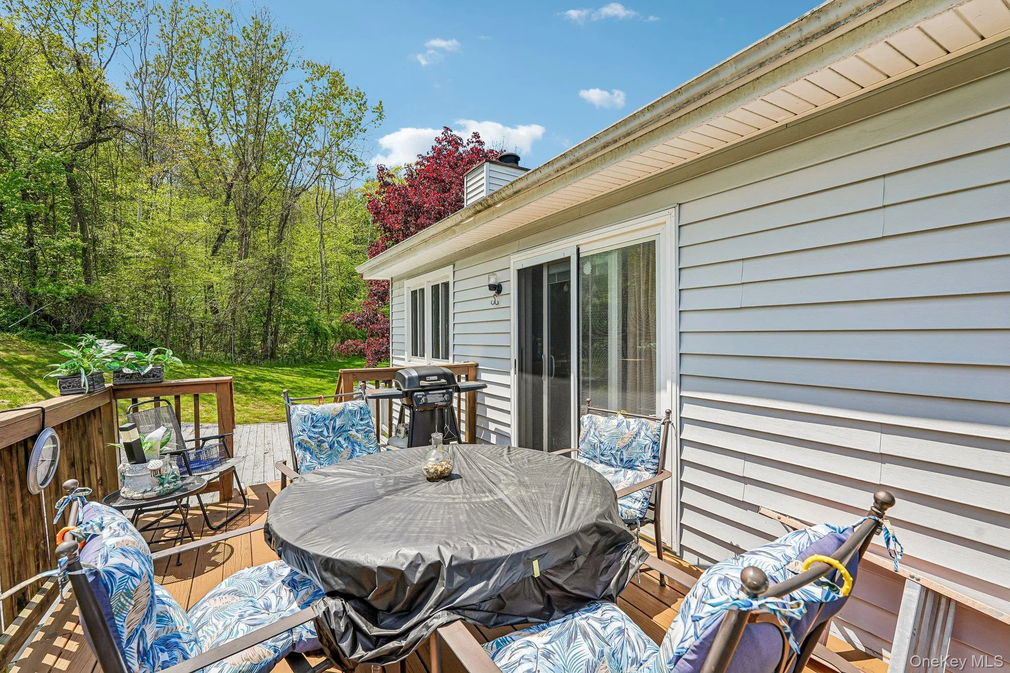 Expansive wood-finish deck with railing, sliding glass door entry, and light-colored siding. some photos may include virtually staged or digitally modified Expansive wood-finish deck with railing, sliding glass door entry, and light-colored siding. some photos may include virtually staged or digitally modified