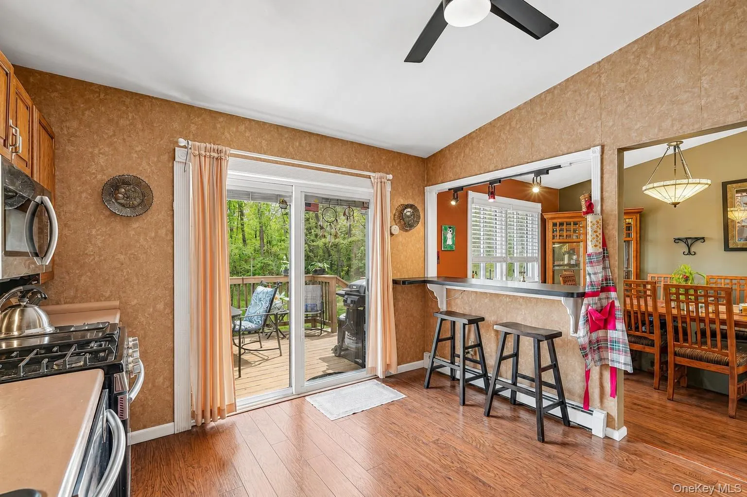 Kitchen featuring wood-finish flooring, warm-toned walls, and a ceiling fan Kitchen featuring wood-finish flooring, warm-toned walls, and a ceiling fan