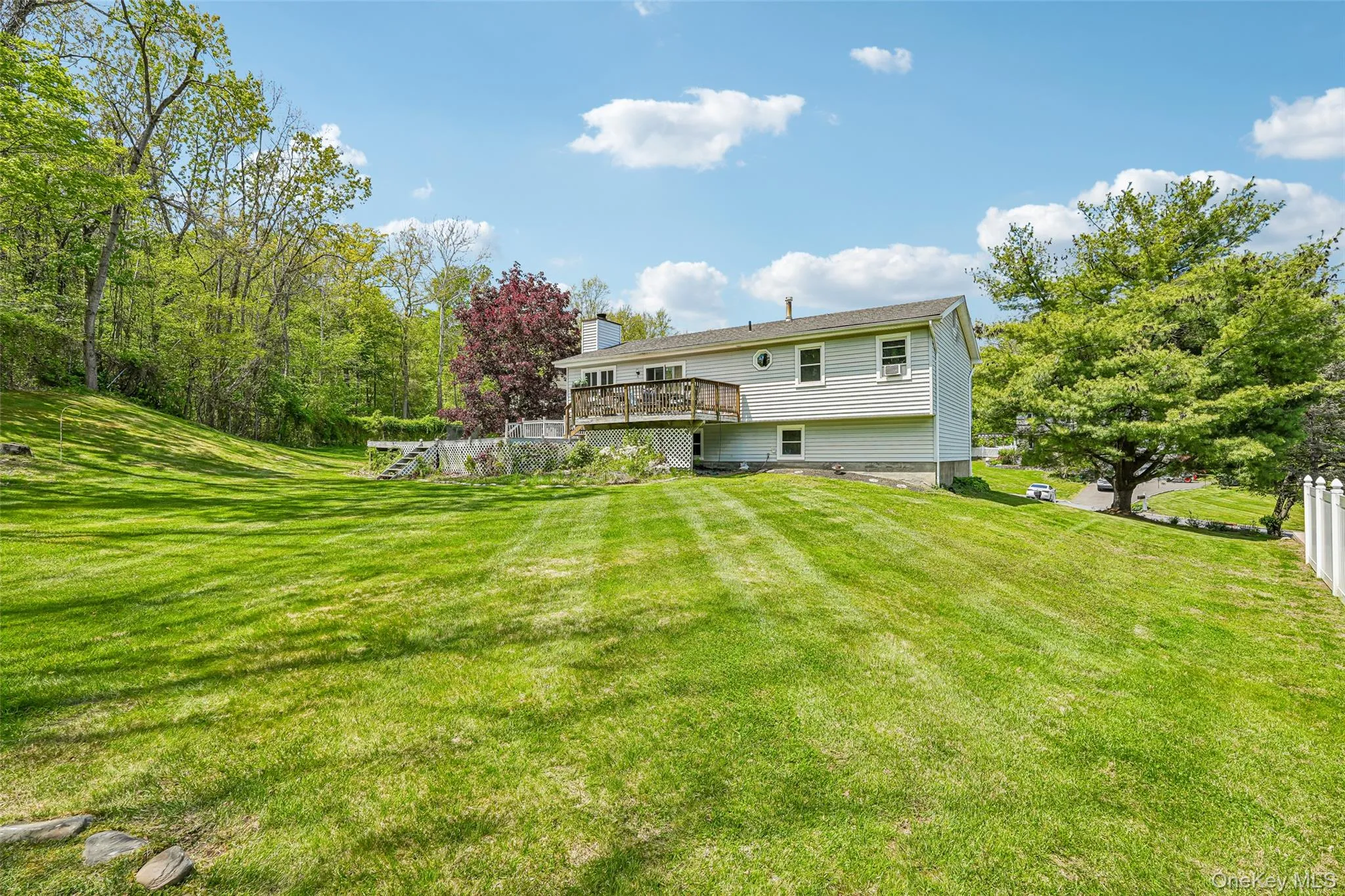 Expansive lawn with mature trees and a multi-level deck. some photos may include virtually staged or digitally modified Expansive lawn with mature trees and a multi-level deck. some photos may include virtually staged or digitally modified