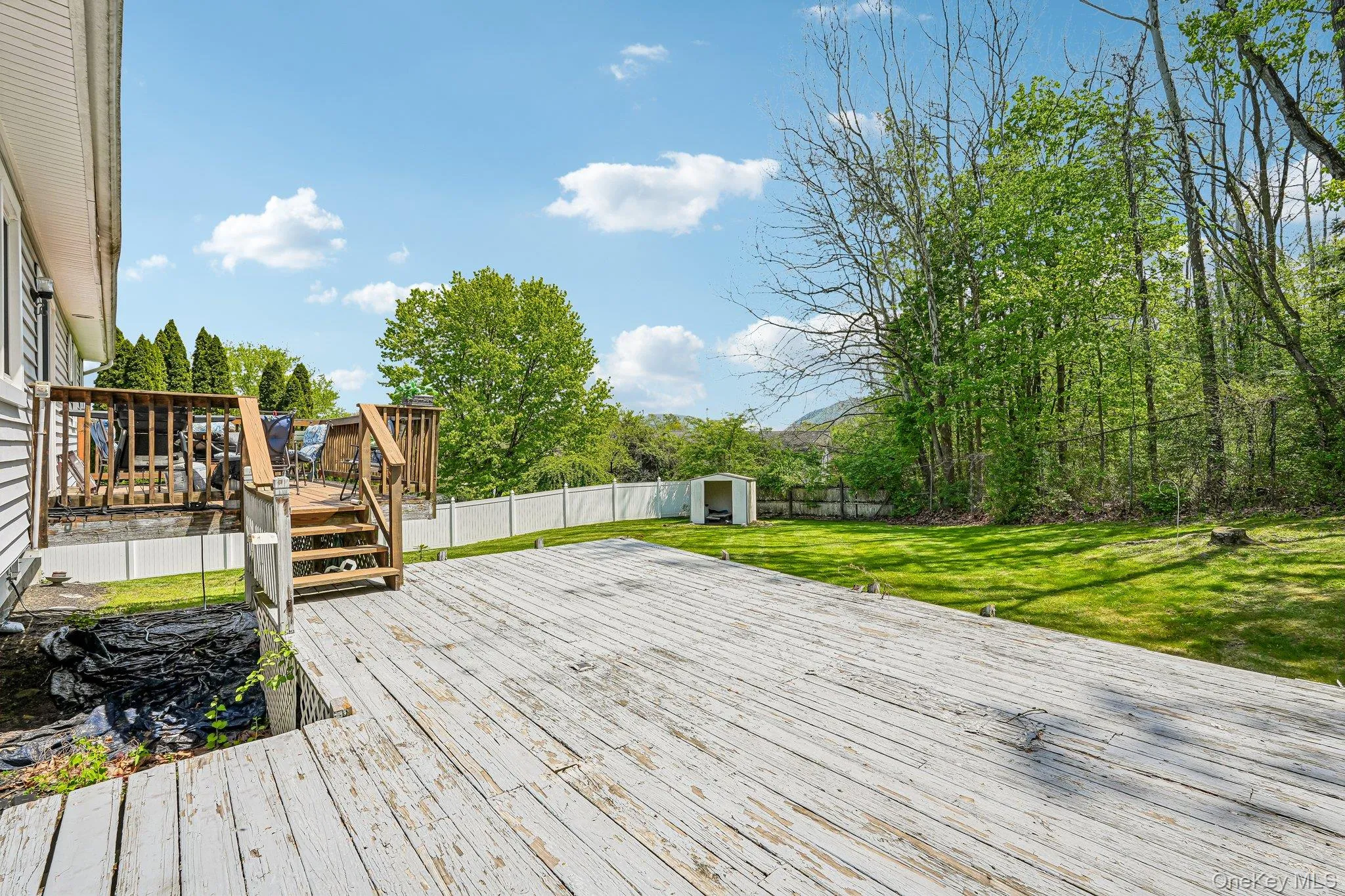 Expansive backyard featuring a multi-level deck, manicured lawn, full privacy fencing, mature trees, and a storage shed. some photos may include virtually staged or digitally modified Expansive backyard featuring a multi-level deck, manicured lawn, full privacy fencing, mature trees, and a storage shed. some photos may include virtually staged or digitally modified