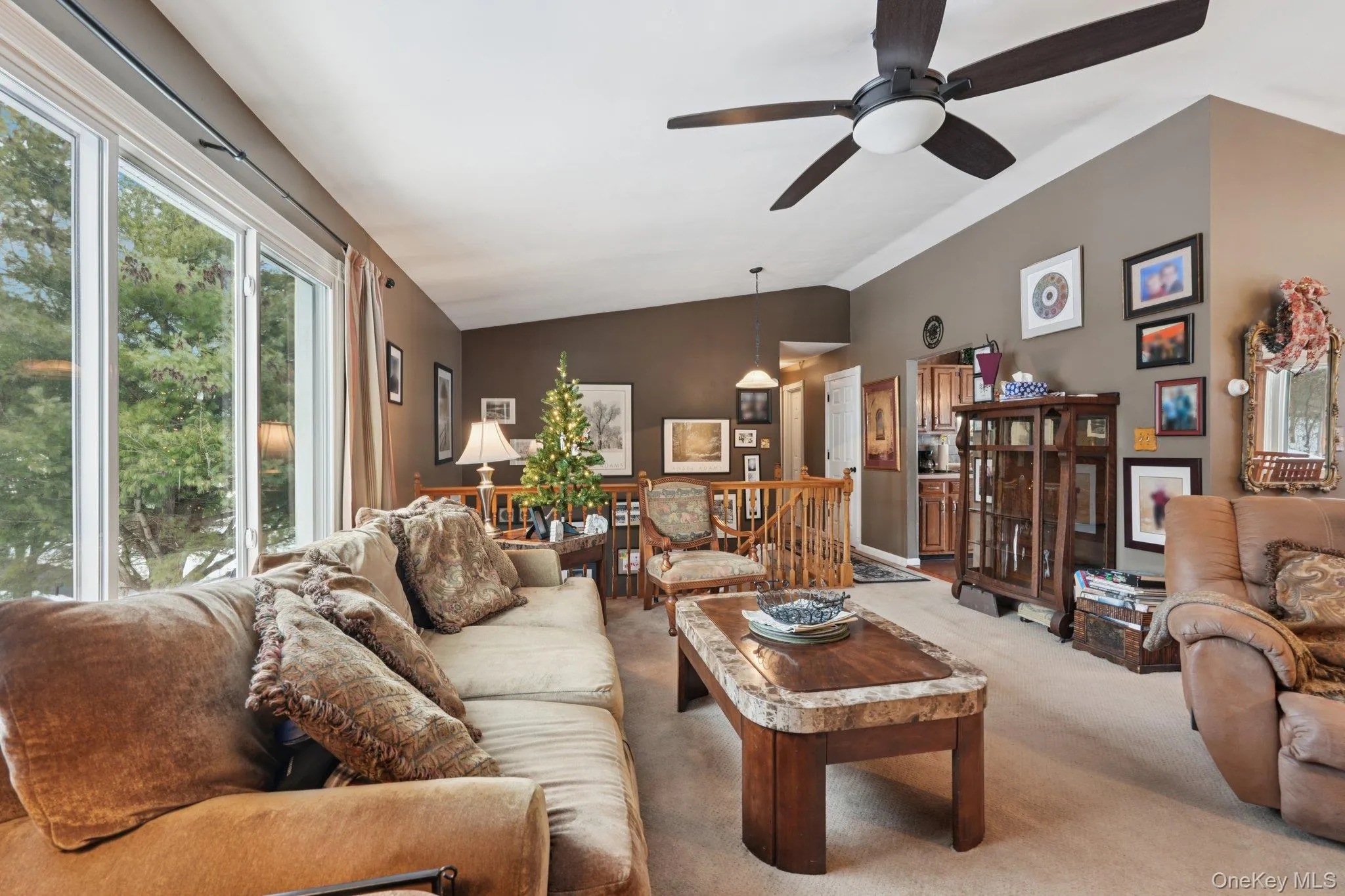 Carpeted living area featuring vaulted ceiling and ceiling fan. some photos may include virtually staged or digitally modified Carpeted living area featuring vaulted ceiling and ceiling fan. some photos may include virtually staged or digitally modified
