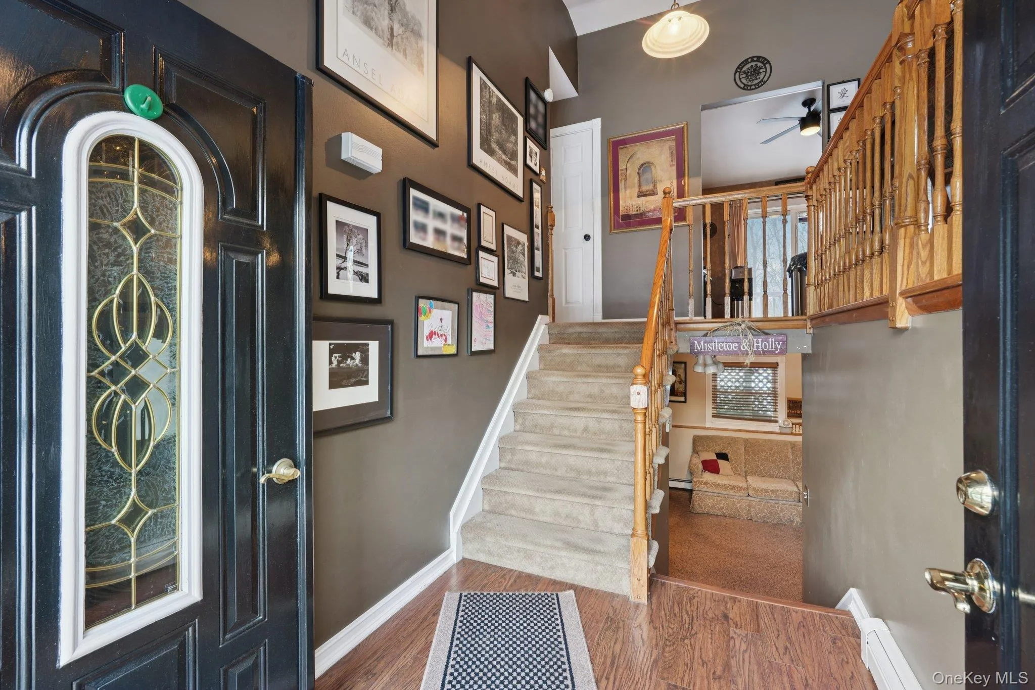 Entry Staircase featuring a baseboard heating, wood finished floors, and ceiling fan Entry Staircase featuring a baseboard heating, wood finished floors, and ceiling fan