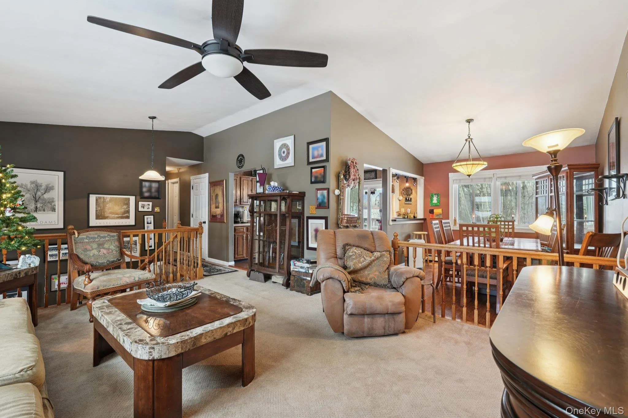 Carpeted living area featuring vaulted ceiling and ceiling fan. some photos may include virtually staged or digitally modified Carpeted living area featuring vaulted ceiling and ceiling fan. some photos may include virtually staged or digitally modified