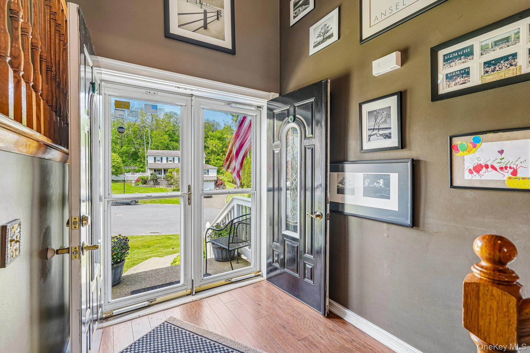 Entryway featuring wood-finish flooring, a decorative front door with an ornate glass insert, and a screen door.some photos may include virtually staged or digitally modified Entryway featuring wood-finish flooring, a decorative front door with an ornate glass insert, and a screen door.some photos may include virtually staged or digitally modified