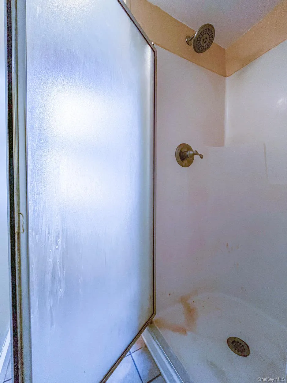 Bathroom with a shower stall and tile patterned flooring Bathroom with a shower stall and tile patterned flooring