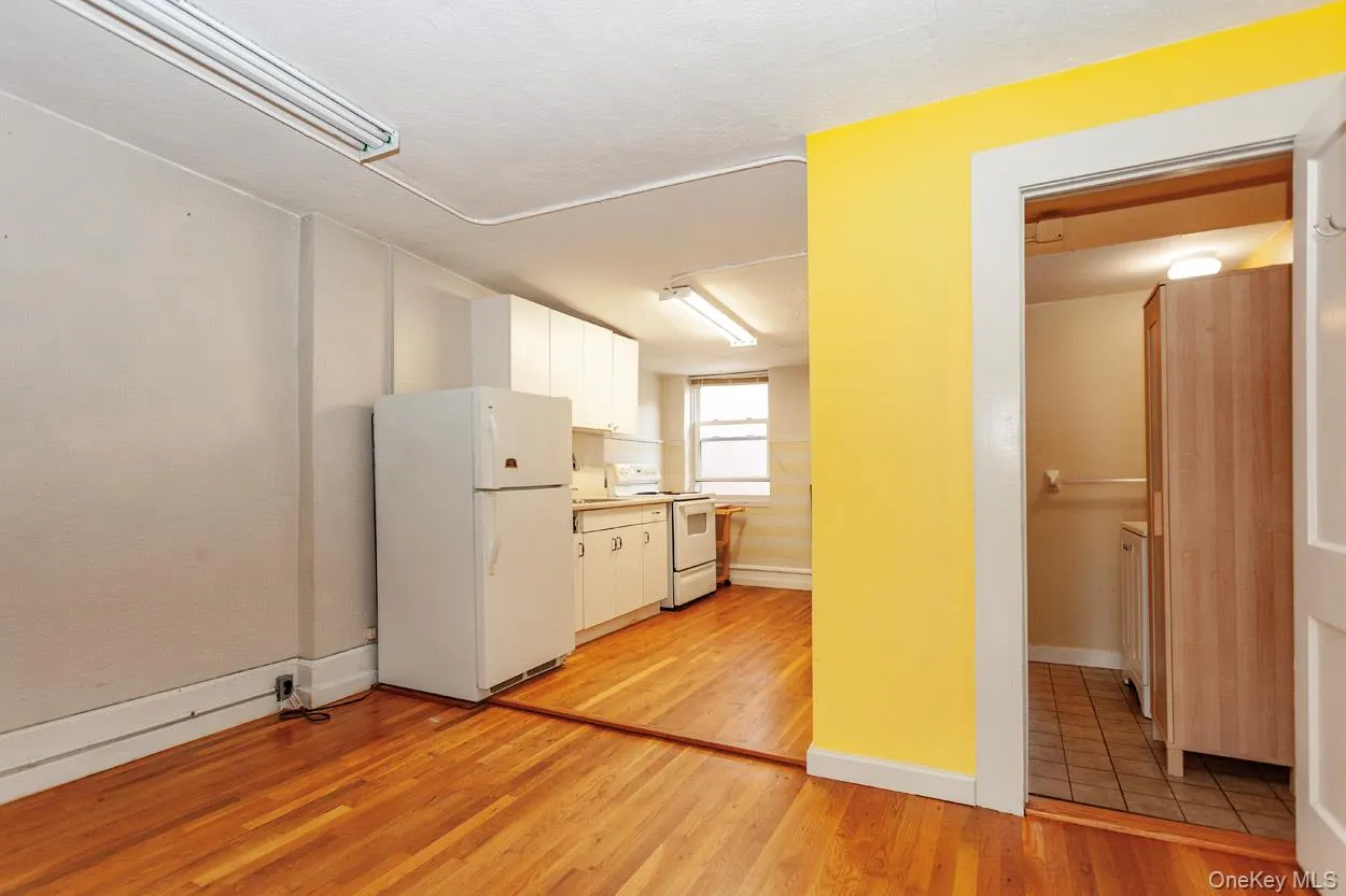 Kitchen featuring white cabinetry, white appliances, light wood-style flooring, and light countertops Kitchen featuring white cabinetry, white appliances, light wood-style flooring, and light countertops