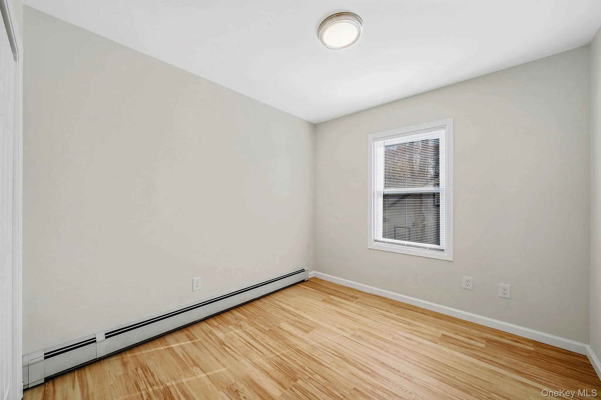 Unfurnished room featuring a baseboard heating unit and light wood-type flooring Unfurnished room featuring a baseboard heating unit and light wood-type flooring
