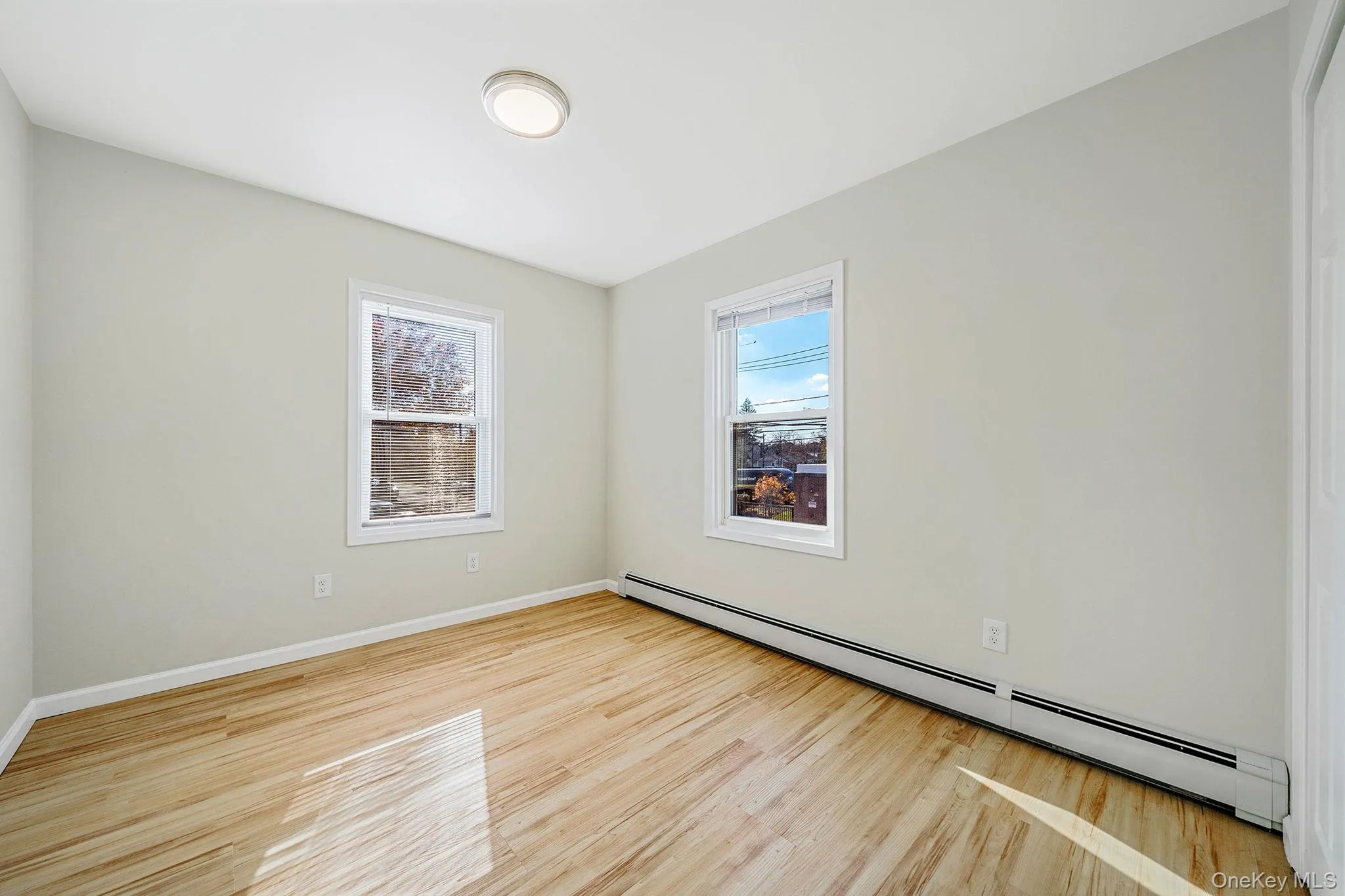 Unfurnished room with a baseboard radiator and light wood-type flooring Unfurnished room with a baseboard radiator and light wood-type flooring