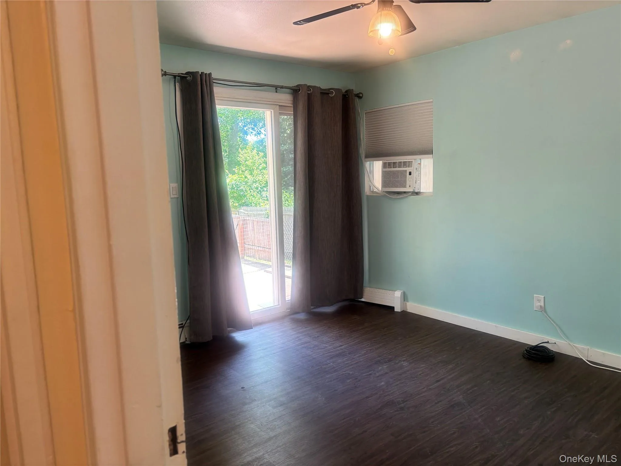 Outside entrance with dark wood-style floors, ceiling fan, cooling unit, and a baseboard heating unit Outside entrance with dark wood-style floors, ceiling fan, cooling unit, and a baseboard heating unit