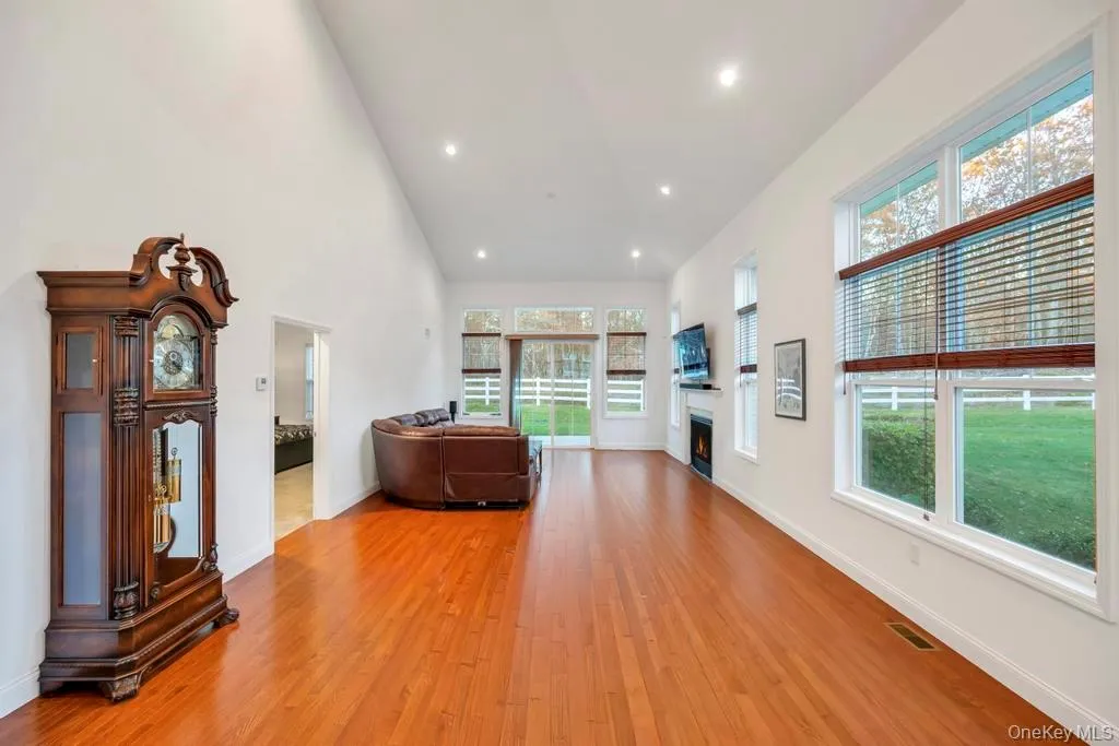 Living room with recessed lighting, high vaulted ceiling, light wood-style floors, and a lit fireplace Living room with recessed lighting, high vaulted ceiling, light wood-style floors, and a lit fireplace