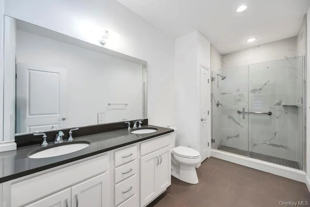 Primary full Bathroom featuring double vanity, dark tile patterned floors, a marble finish shower, and recessed lighting Primary full Bathroom featuring double vanity, dark tile patterned floors, a marble finish shower, and recessed lighting
