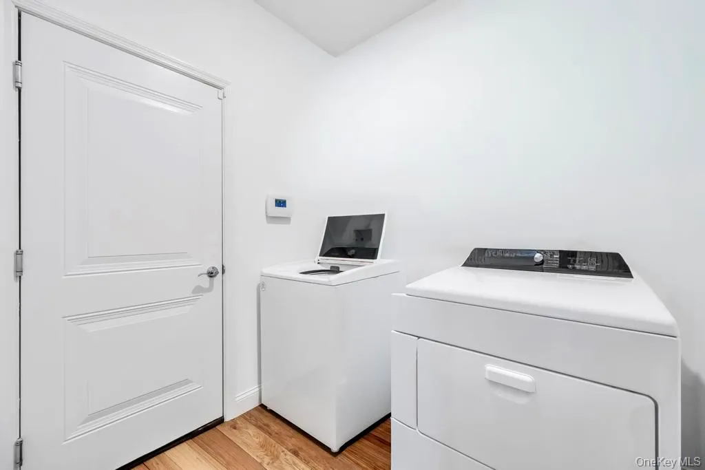 Laundry room featuring light wood-type flooring and separate washer and dryer Laundry room featuring light wood-type flooring and separate washer and dryer