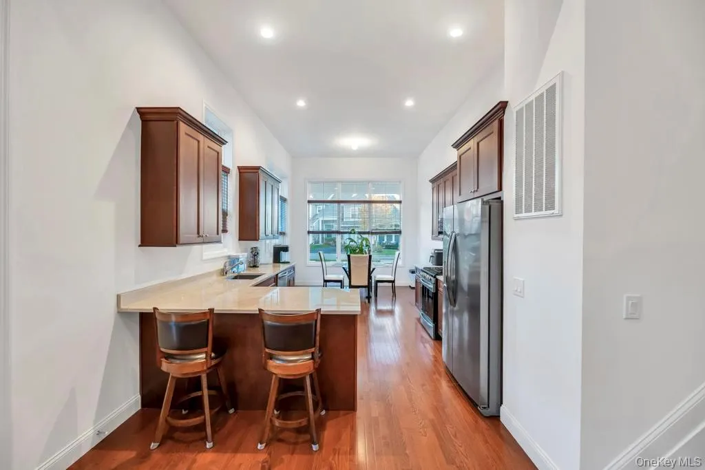 Kitchen featuring a peninsula, a breakfast bar, dark wood-style floors, appliances with stainless steel finishes, and dark brown cabinetry Kitchen featuring a peninsula, a breakfast bar, dark wood-style floors, appliances with stainless steel finishes, and dark brown cabinetry