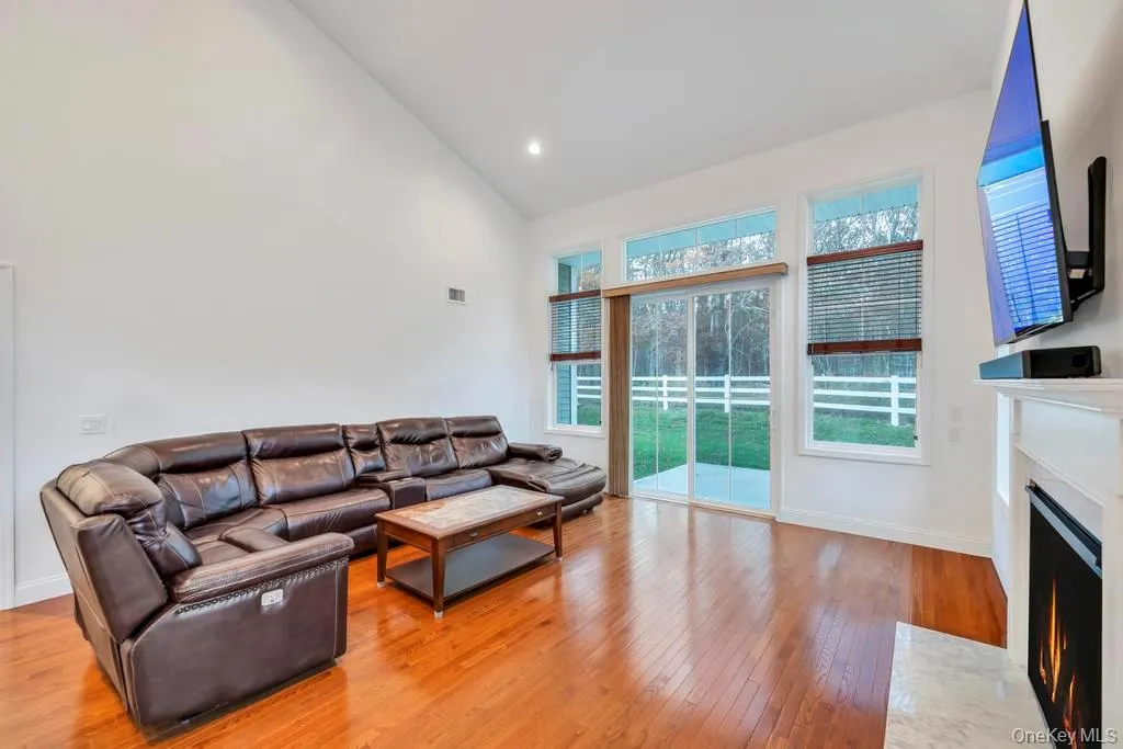 Living area featuring high vaulted ceiling, a fireplace with flush hearth, light wood-style flooring, and recessed lighting Living area featuring high vaulted ceiling, a fireplace with flush hearth, light wood-style flooring, and recessed lighting