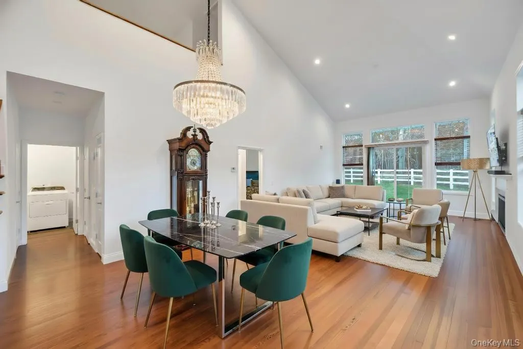 Dining area featuring wood finished floors, high vaulted ceiling, a chandelier, washer / clothes dryer, and a fireplace Dining area featuring wood finished floors, high vaulted ceiling, a chandelier, washer / clothes dryer, and a fireplace