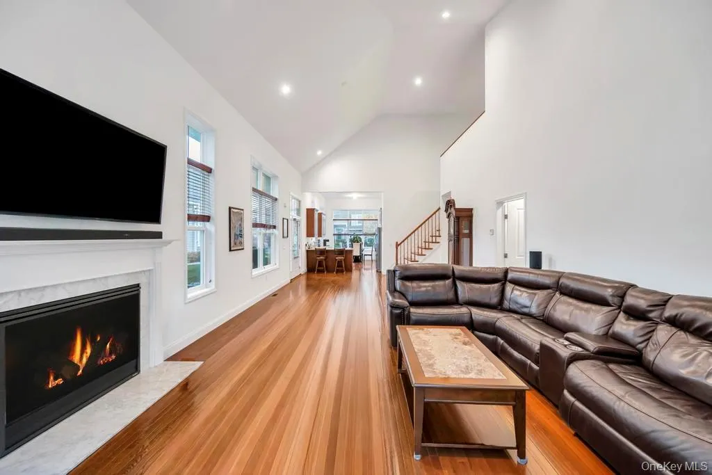 Living area featuring high vaulted ceiling, light wood finished floors, a high end fireplace, recessed lighting, and stairs Living area featuring high vaulted ceiling, light wood finished floors, a high end fireplace, recessed lighting, and stairs