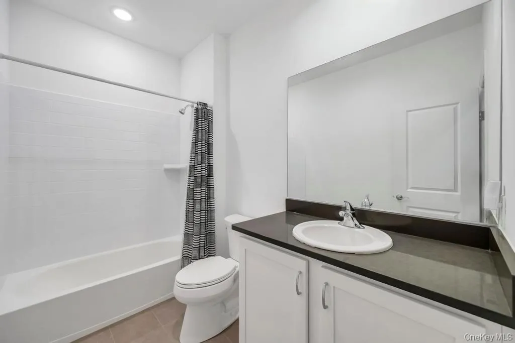 Full bathroom featuring shower / tub combo with curtain, vanity, and light tile patterned floors Full bathroom featuring shower / tub combo with curtain, vanity, and light tile patterned floors