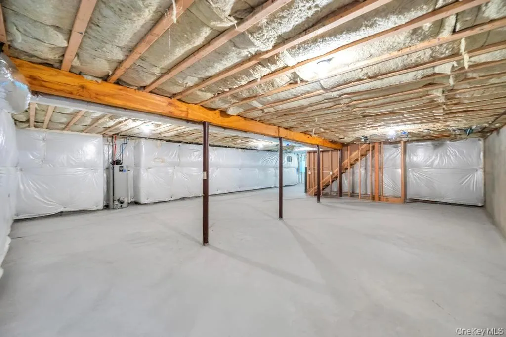Unfinished below grade area with stairs and gas water heater Unfinished below grade area with stairs and gas water heater
