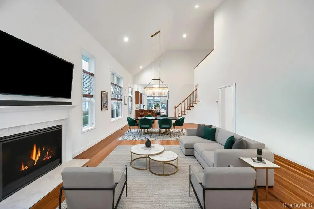 Living area with healthy amount of natural light, a high end fireplace, high vaulted ceiling, stairway, and wood finished floors Living area with healthy amount of natural light, a high end fireplace, high vaulted ceiling, stairway, and wood finished floors