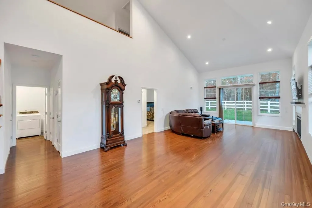 Living room featuring high vaulted ceiling, wood finished floors, washer / clothes dryer, a glass covered fireplace, and recessed lighting Living room featuring high vaulted ceiling, wood finished floors, washer / clothes dryer, a glass covered fireplace, and recessed lighting