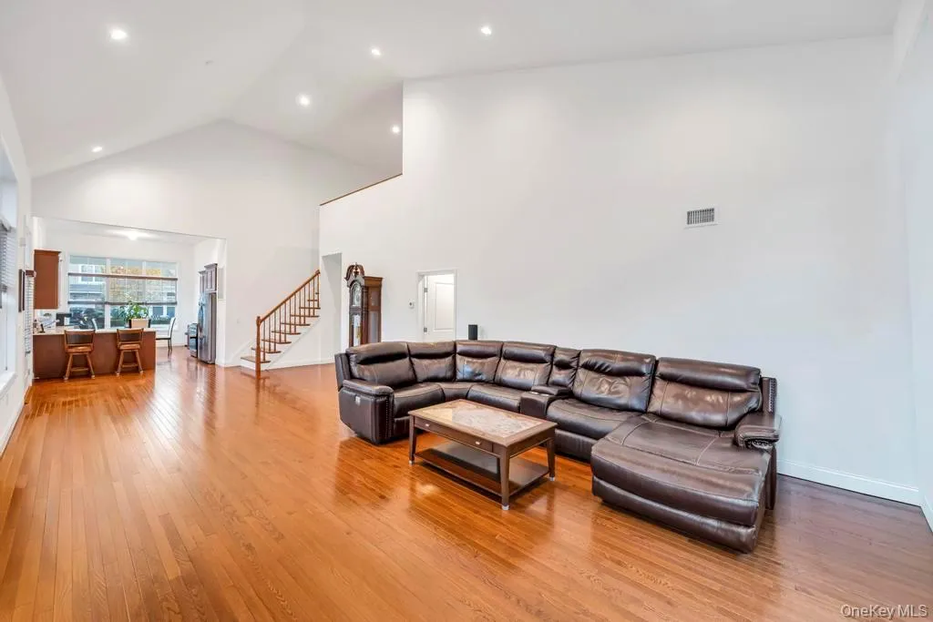 Living room with light wood-style flooring, stairs, high vaulted ceiling, and recessed lighting Living room with light wood-style flooring, stairs, high vaulted ceiling, and recessed lighting