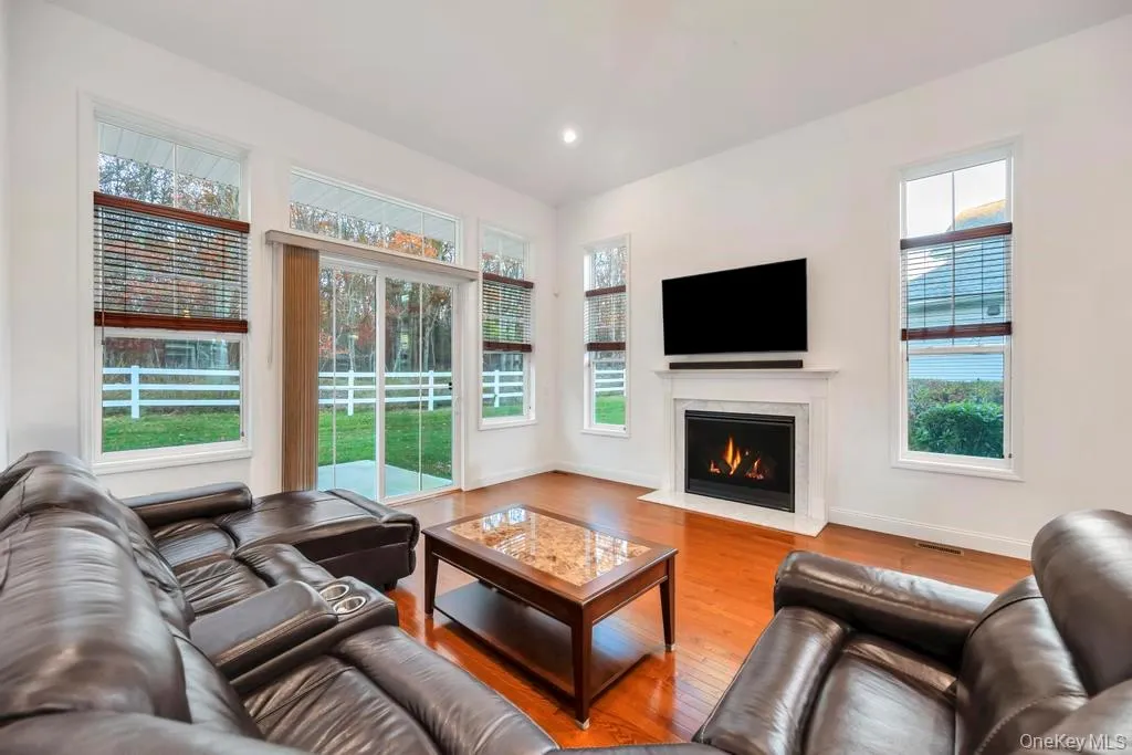 Living area with wood finished floors, a high end fireplace, and recessed lighting Living area with wood finished floors, a high end fireplace, and recessed lighting