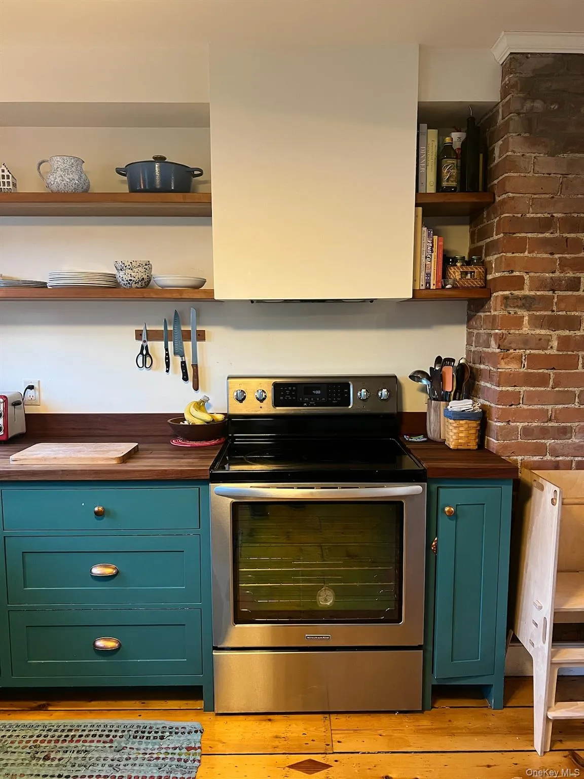 Kitchen featuring open shelves, stainless steel electric range, green cabinets, butcher block counters, and light wood-type flooring Kitchen featuring open shelves, stainless steel electric range, green cabinets, butcher block counters, and light wood-type flooring