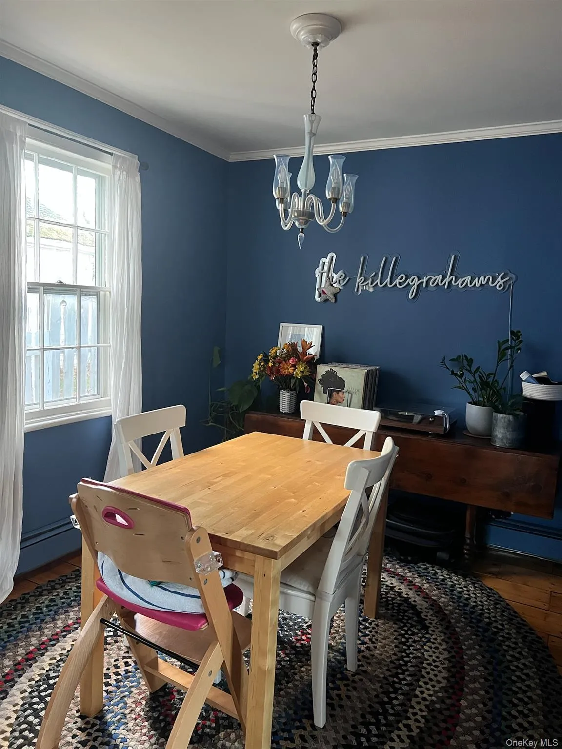 Dining area featuring crown molding, wood finished floors, a chandelier, and a baseboard heating unit Dining area featuring crown molding, wood finished floors, a chandelier, and a baseboard heating unit