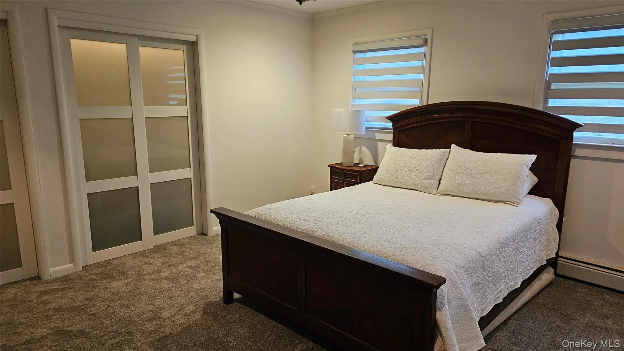 Bedroom featuring carpet, crown molding, and a baseboard radiator Bedroom featuring carpet, crown molding, and a baseboard radiator