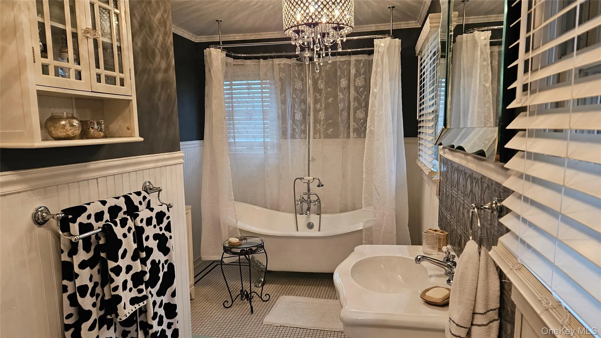 Full bath featuring ornamental molding, a soaking tub, a chandelier, wainscoting, and vanity Full bath featuring ornamental molding, a soaking tub, a chandelier, wainscoting, and vanity