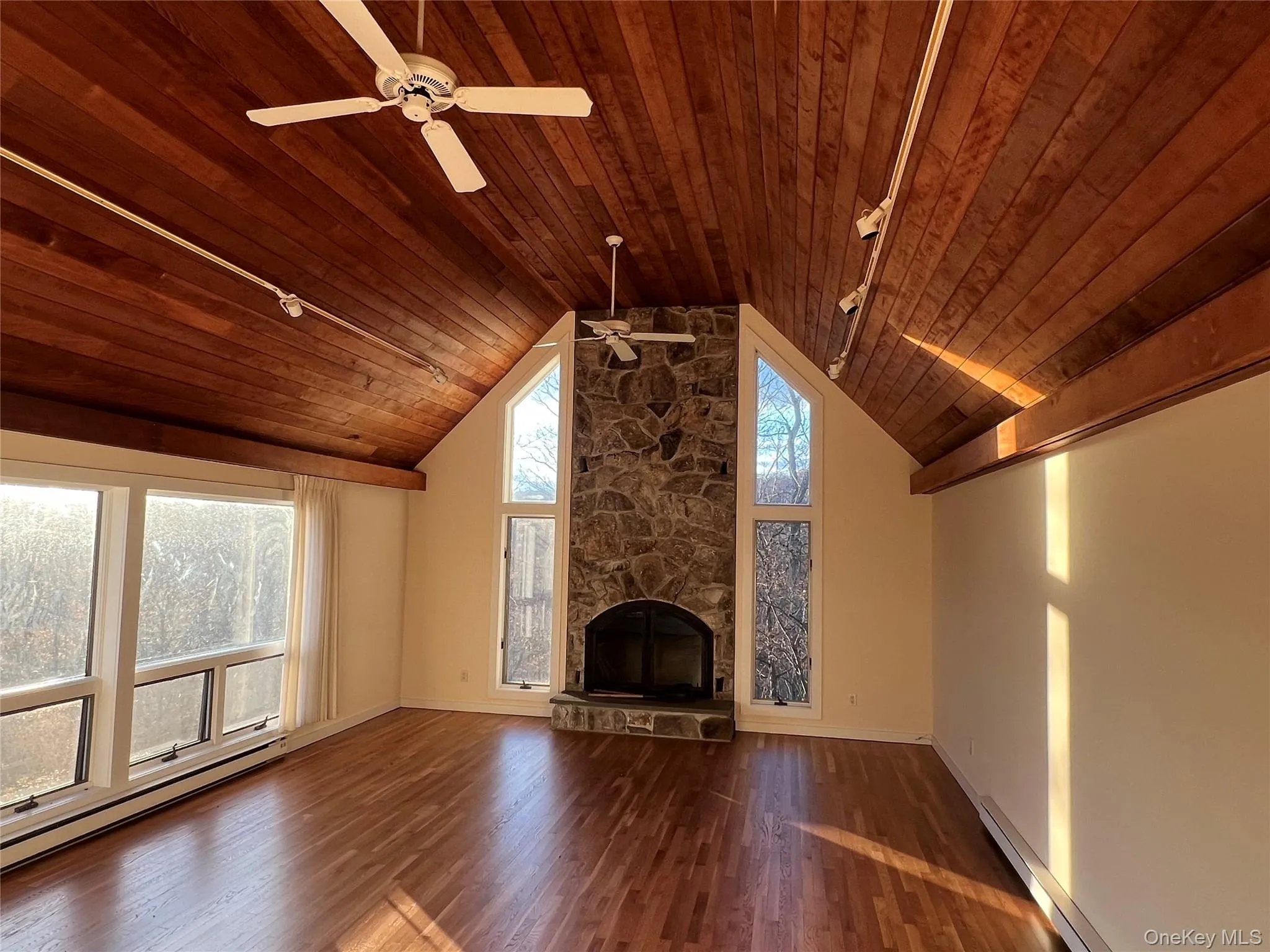 Unfurnished living room featuring wood ceiling, a baseboard radiator, dark wood-style flooring, a fireplace, and high vaulted ceiling Unfurnished living room featuring wood ceiling, a baseboard radiator, dark wood-style flooring, a fireplace, and high vaulted ceiling