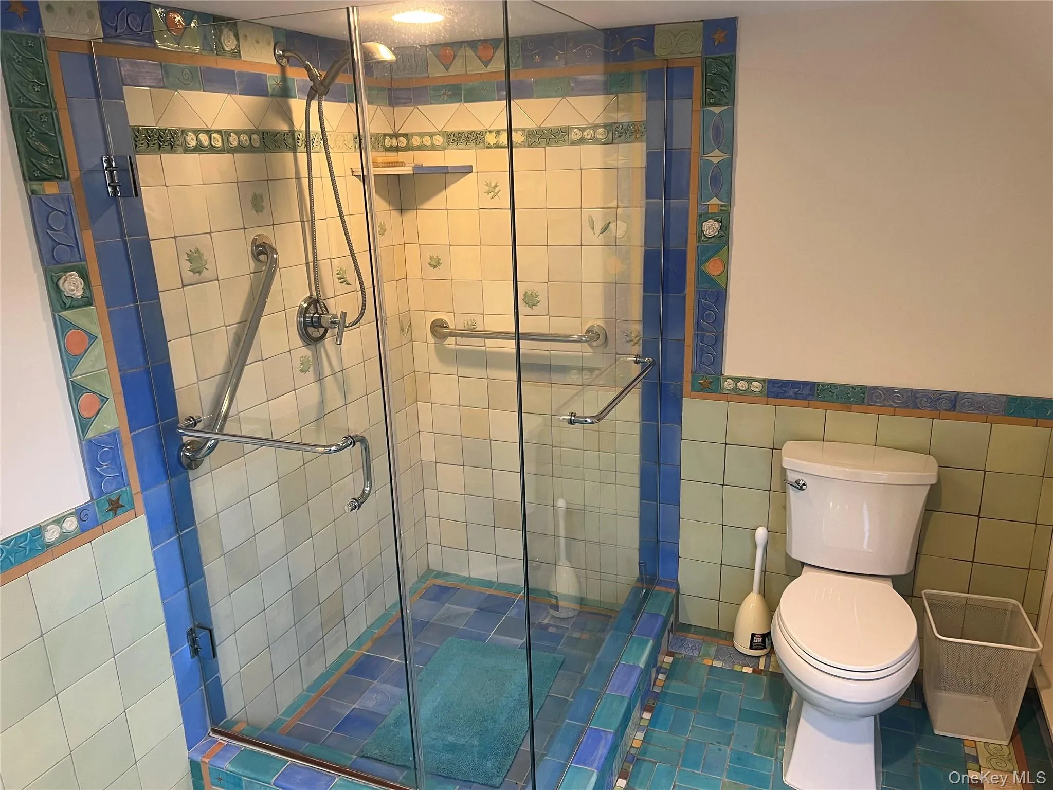 Bathroom with tile walls, wainscoting, a stall shower, and tile patterned floors Bathroom with tile walls, wainscoting, a stall shower, and tile patterned floors