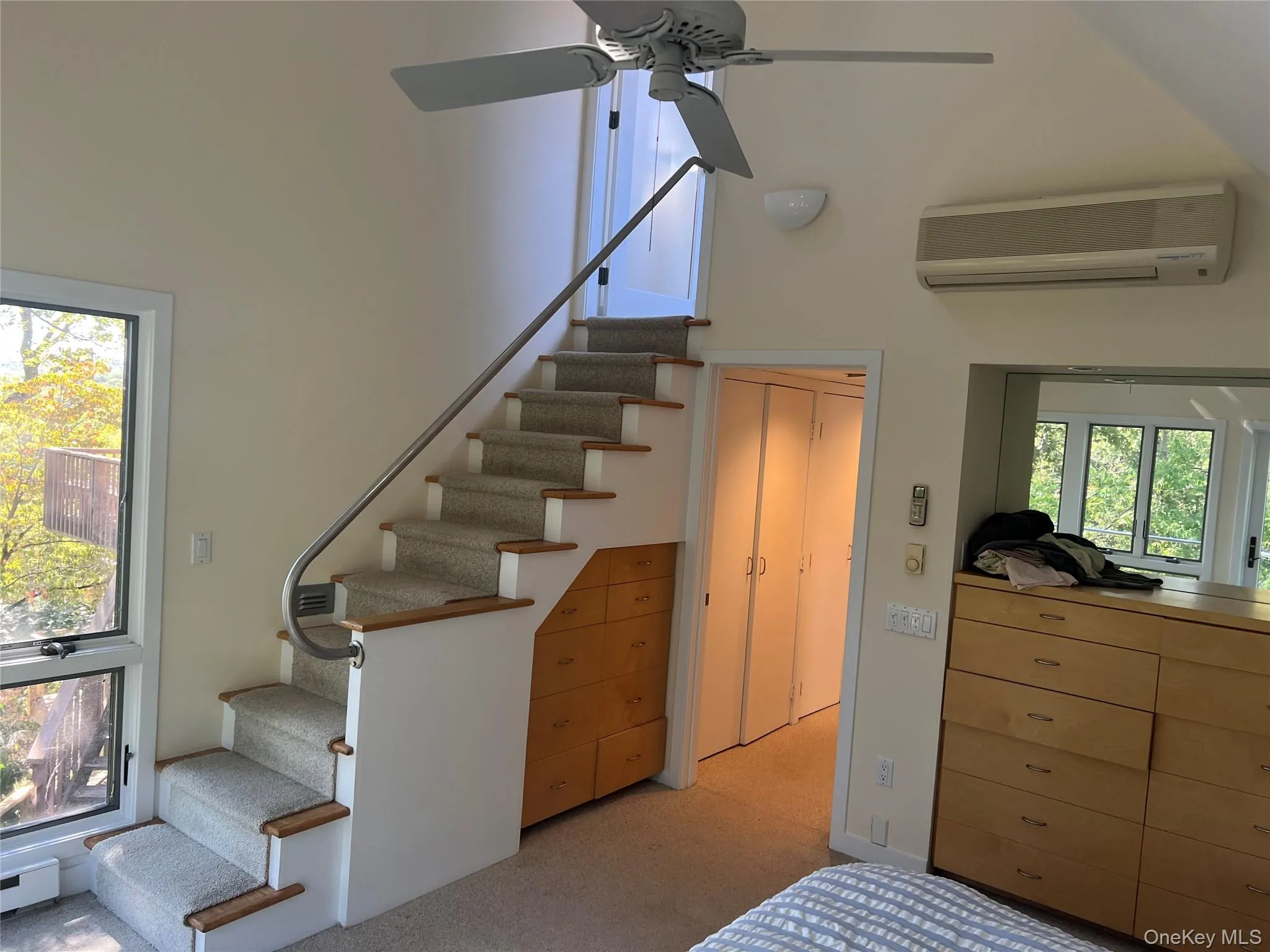 Stairs to private dressing room/closet (master bedroom),featuring a wall unit AC, carpet floors, a towering ceiling, and ceiling fan Stairs to private dressing room/closet (master bedroom),featuring a wall unit AC, carpet floors, a towering ceiling, and ceiling fan