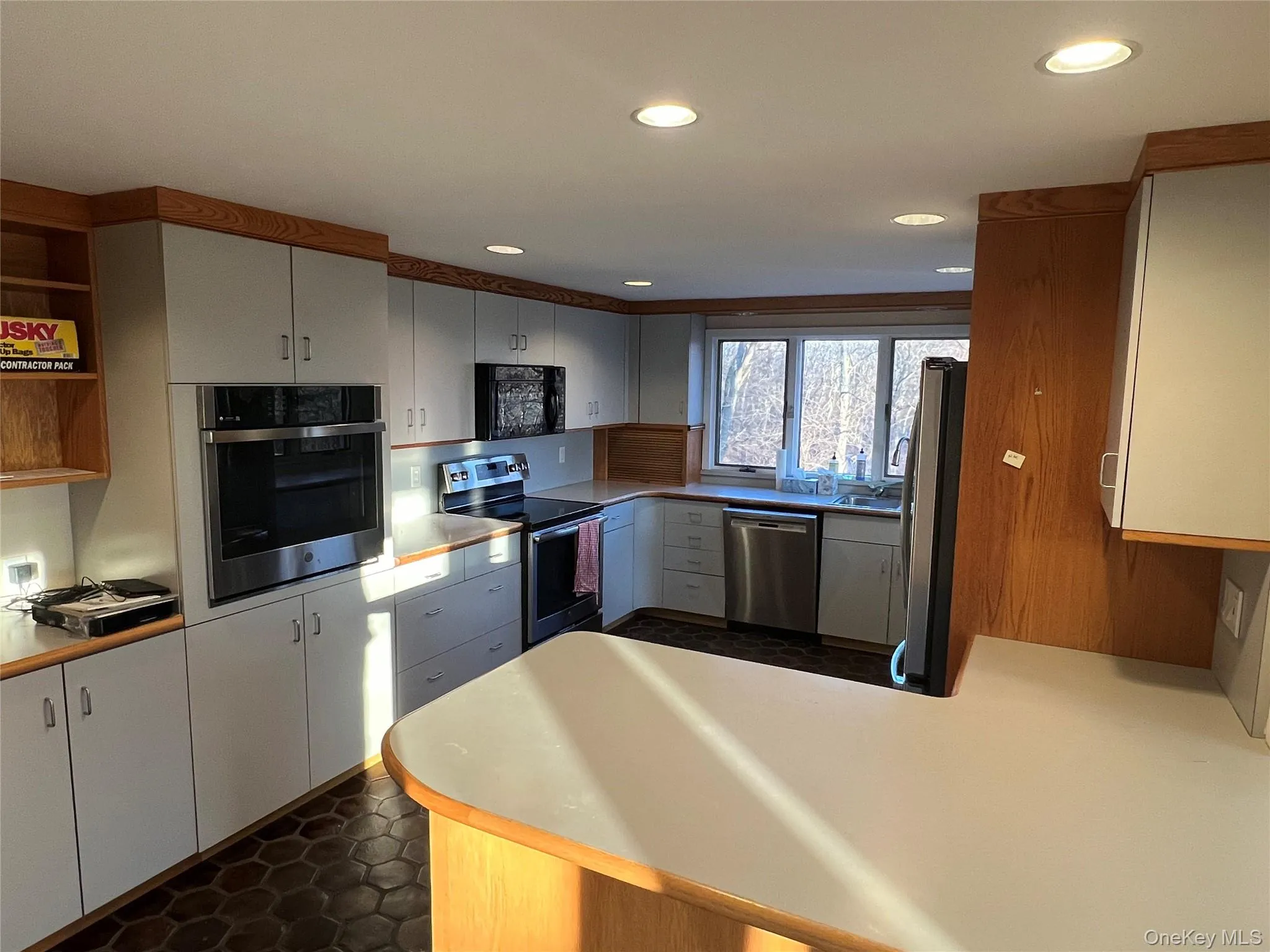 Kitchen featuring appliances with stainless steel finishes, a peninsula, open shelves, light countertops, and white cabinets Kitchen featuring appliances with stainless steel finishes, a peninsula, open shelves, light countertops, and white cabinets