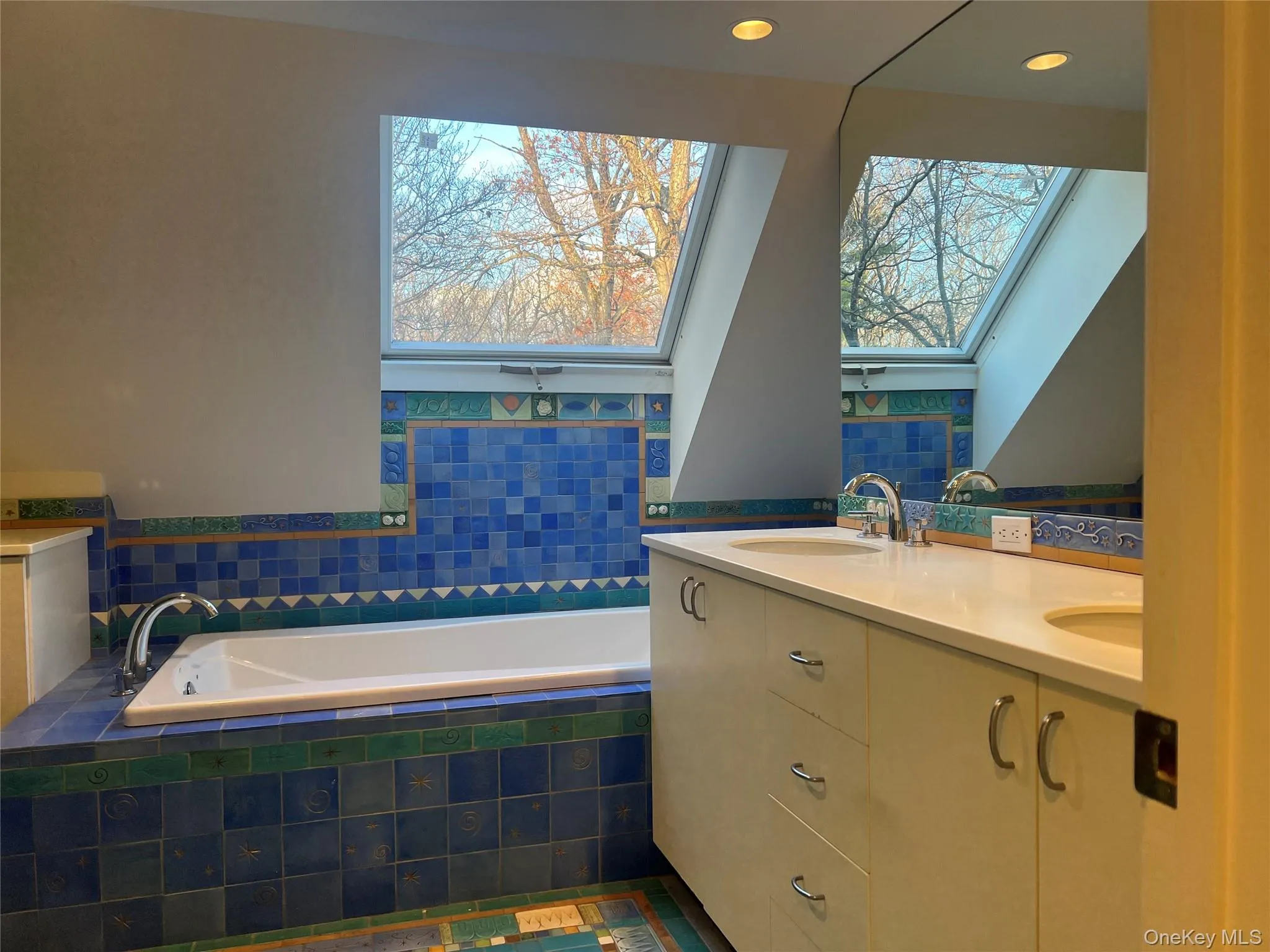 Full bathroom featuring a garden tub, double vanity, and a skylight Full bathroom featuring a garden tub, double vanity, and a skylight