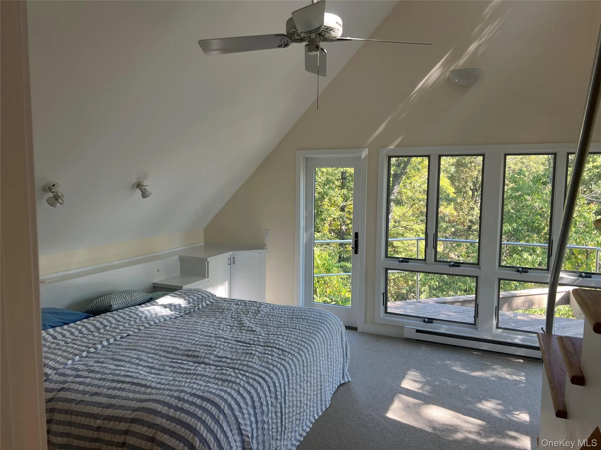 Carpeted master bedroom (main floor).with a baseboard radiator, vaulted ceiling, ceiling fan, and access to outside Carpeted master bedroom (main floor).with a baseboard radiator, vaulted ceiling, ceiling fan, and access to outside