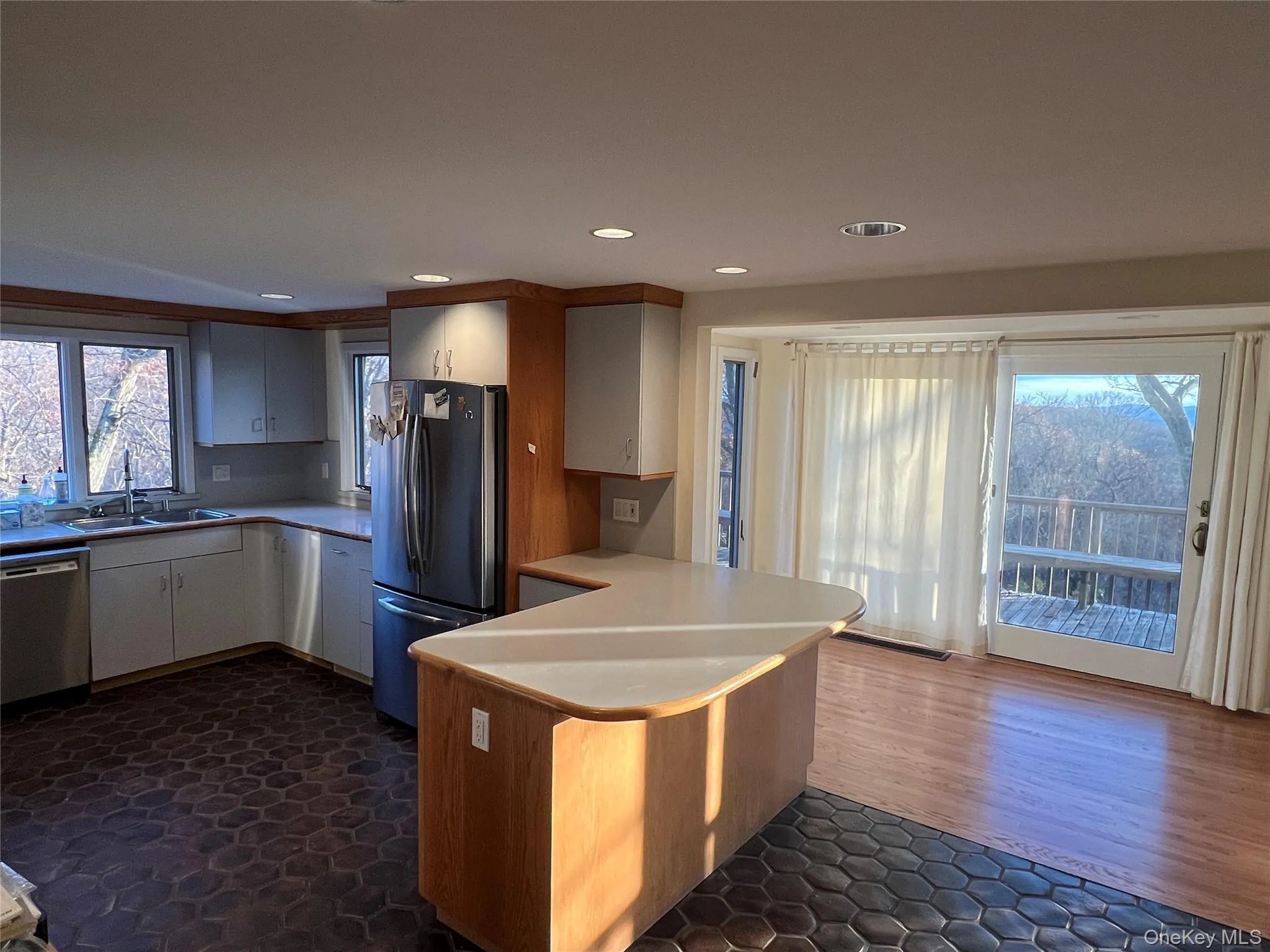 Kitchen featuring light countertops, appliances with stainless steel finishes, a peninsula, recessed lighting, and white cabinets Kitchen featuring light countertops, appliances with stainless steel finishes, a peninsula, recessed lighting, and white cabinets