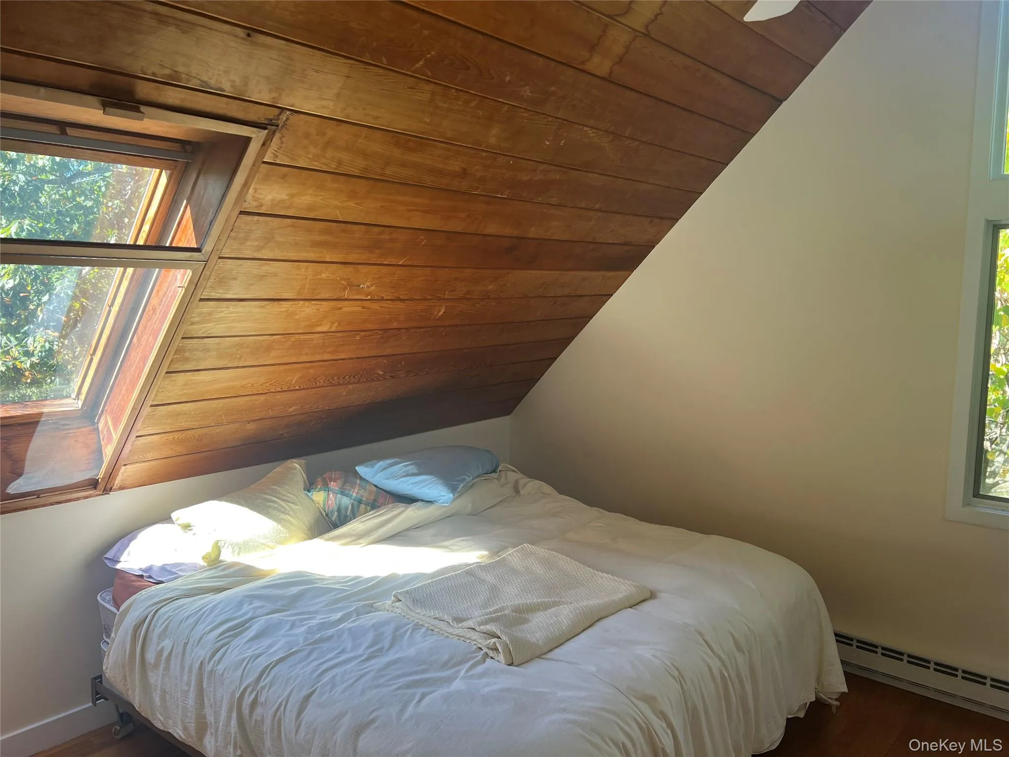 Bedroom with multiple windows, lofted ceiling, wood ceiling, dark wood-type flooring, and a baseboard heating unit Bedroom with multiple windows, lofted ceiling, wood ceiling, dark wood-type flooring, and a baseboard heating unit