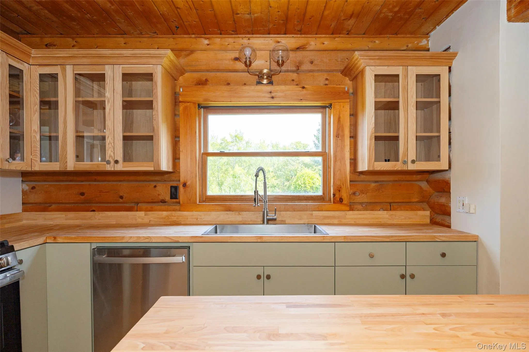 Kitchen with glass insert cabinets, butcher block countertops, stainless steel appliances, and wooden ceiling Kitchen with glass insert cabinets, butcher block countertops, stainless steel appliances, and wooden ceiling