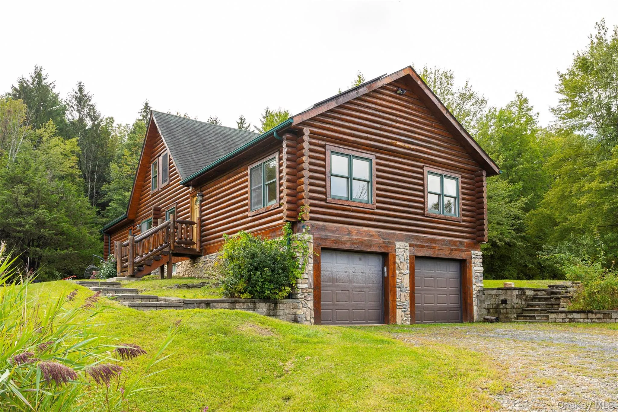 View of side of home featuring stairway, log exterior, driveway, a garage, and a lawn View of side of home featuring stairway, log exterior, driveway, a garage, and a lawn