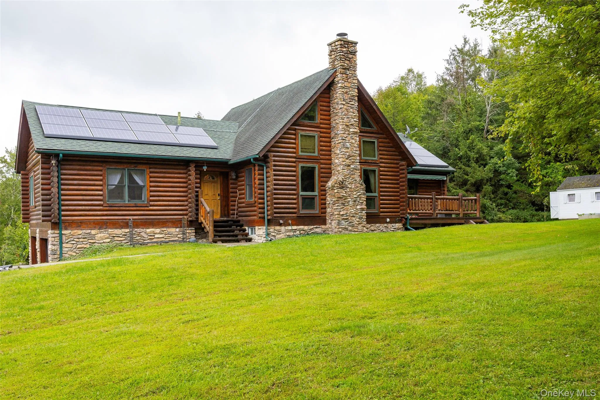Rear view of house featuring a yard, solar panels, a shingled roof, and a chimney Rear view of house featuring a yard, solar panels, a shingled roof, and a chimney